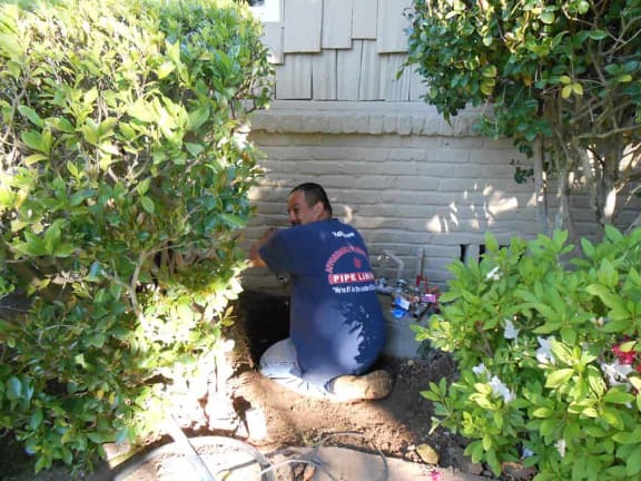 Man working under the side of a house